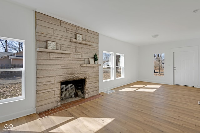 unfurnished living room with a wealth of natural light, baseboards, wood finished floors, and a fireplace