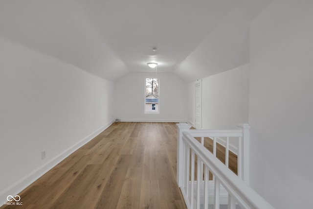 additional living space with lofted ceiling, light wood-style flooring, and baseboards