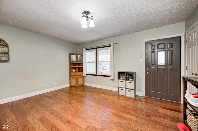 entrance foyer featuring visible vents, a textured ceiling, baseboards, and light wood-style floors