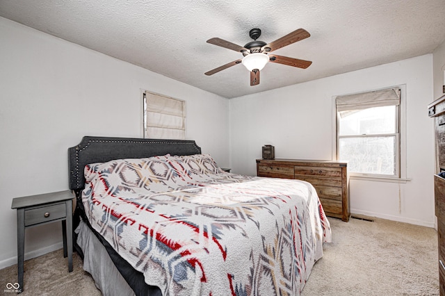 bedroom featuring light carpet, baseboards, a textured ceiling, and ceiling fan