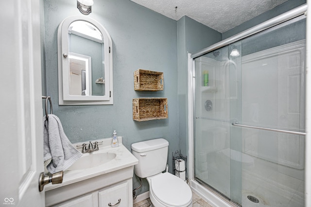 full bath featuring toilet, a stall shower, a textured ceiling, and vanity