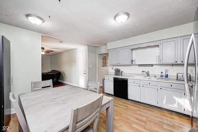 kitchen featuring a sink, light wood-style floors, light countertops, decorative backsplash, and dishwasher