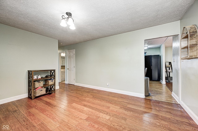 empty room featuring baseboards, light wood finished floors, and a textured ceiling