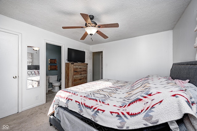 bedroom with carpet, ensuite bath, a ceiling fan, and a textured ceiling