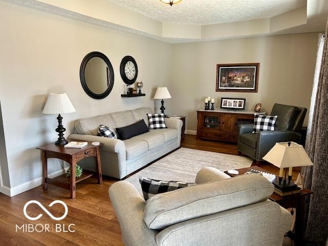 living room featuring a textured ceiling, baseboards, and wood finished floors