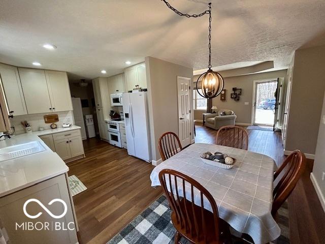 dining area featuring recessed lighting, baseboards, an inviting chandelier, and dark wood-style flooring