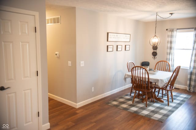 dining area featuring dark wood-style floors, visible vents, and baseboards