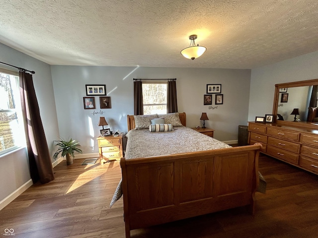 bedroom featuring dark wood finished floors, a textured ceiling, and baseboards