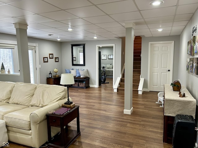 living room with dark wood-type flooring, baseboards, stairway, a drop ceiling, and recessed lighting