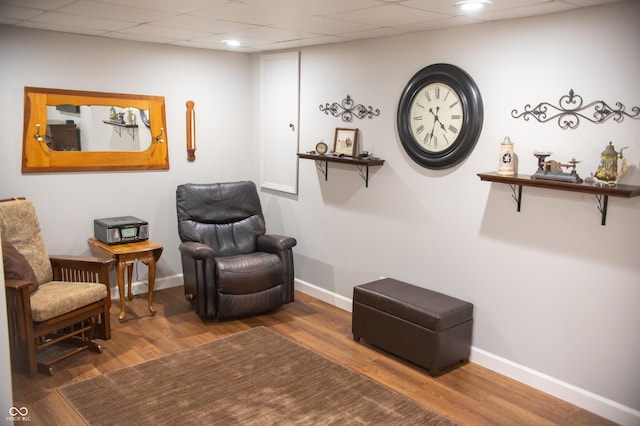 sitting room with a paneled ceiling, baseboards, and wood finished floors