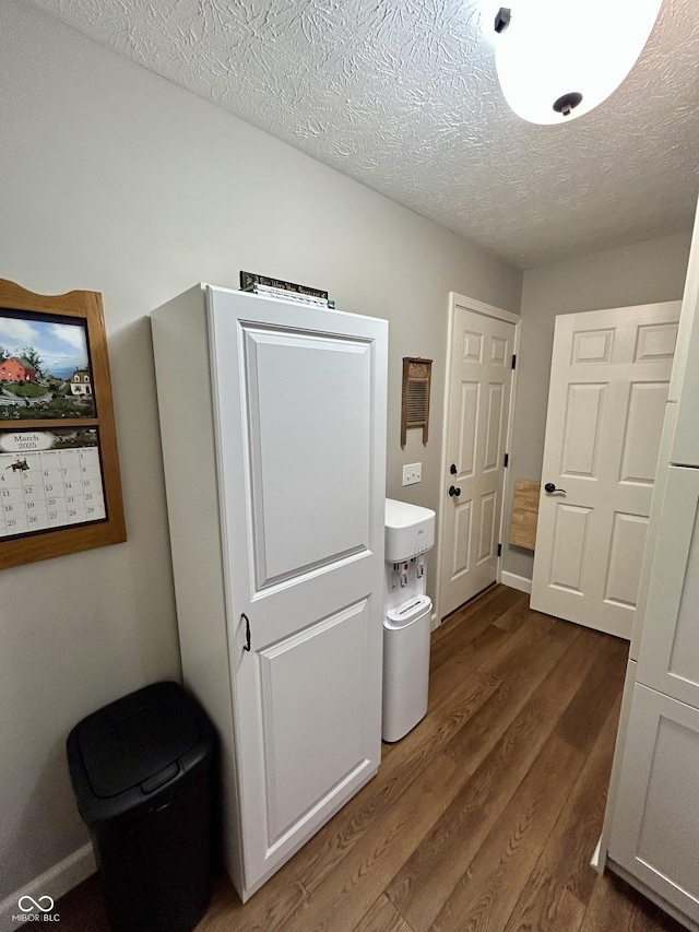 hall with dark wood finished floors and a textured ceiling