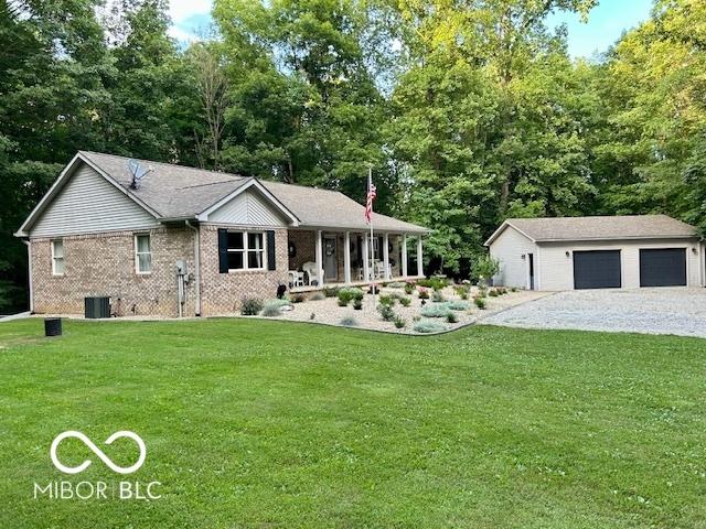 single story home featuring brick siding, a front yard, central AC unit, a garage, and an outbuilding