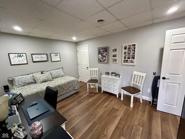 bedroom with visible vents, a drop ceiling, baseboards, and wood finished floors