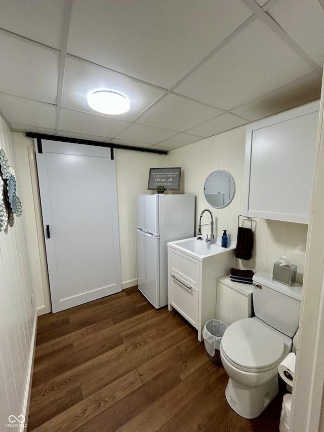 bathroom featuring a drop ceiling, toilet, wood finished floors, and vanity