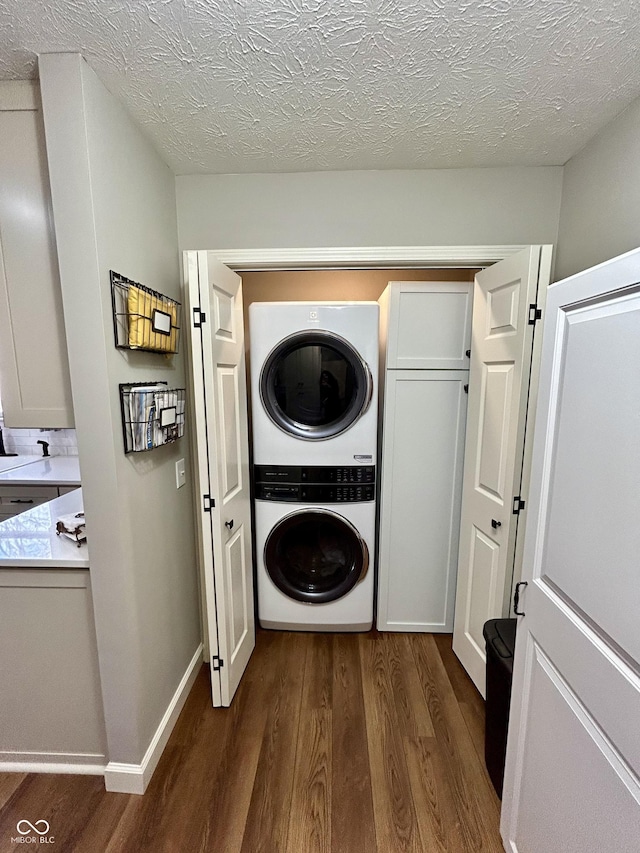 washroom with baseboards, laundry area, a textured ceiling, stacked washer / drying machine, and dark wood-style flooring