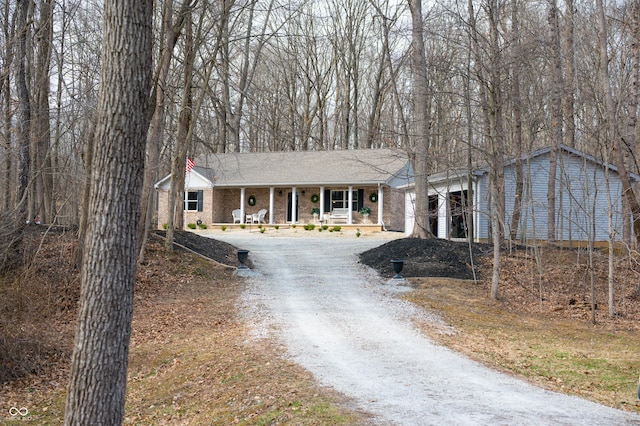 view of front facade with brick siding, a porch, and dirt driveway