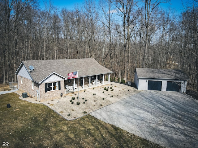 view of front of home with central air condition unit, driveway, a porch, an outdoor structure, and a front yard