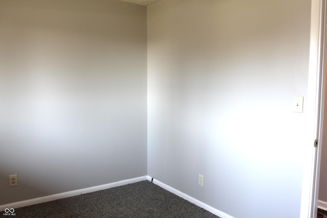 spare room featuring baseboards and dark colored carpet