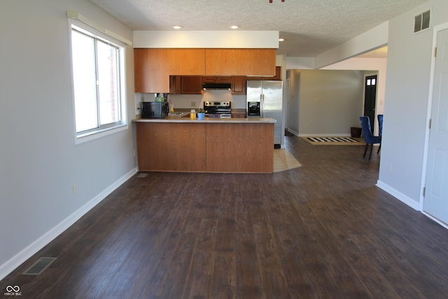 kitchen with visible vents, appliances with stainless steel finishes, a peninsula, and brown cabinetry