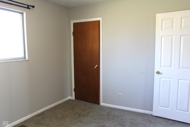 unfurnished bedroom featuring baseboards and dark colored carpet