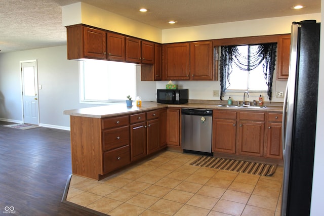 kitchen featuring recessed lighting, appliances with stainless steel finishes, a peninsula, a textured ceiling, and a sink