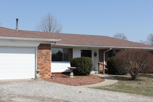 single story home featuring brick siding, a garage, and roof with shingles