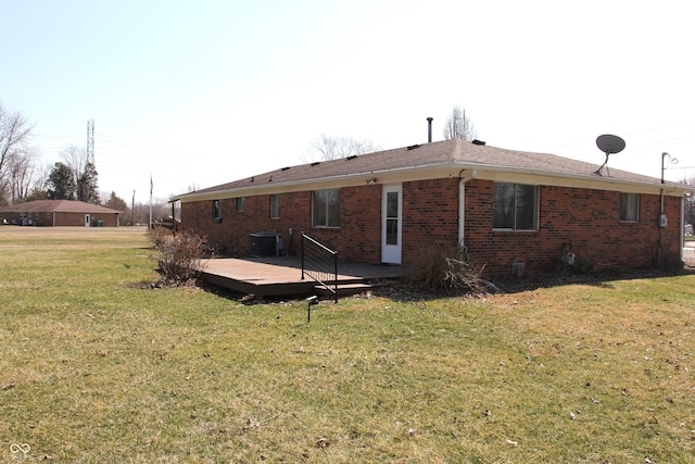 rear view of property with brick siding, central air condition unit, a yard, and a deck