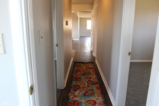 corridor with dark wood-type flooring and baseboards