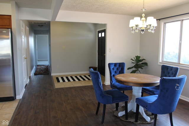 dining space with baseboards, wood finished floors, a textured ceiling, and a chandelier