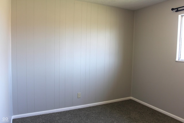 empty room with dark carpet and baseboards