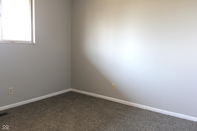 spare room with visible vents, dark carpet, and baseboards