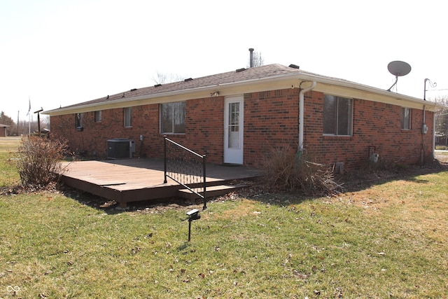 rear view of property with brick siding, a lawn, a wooden deck, and central AC