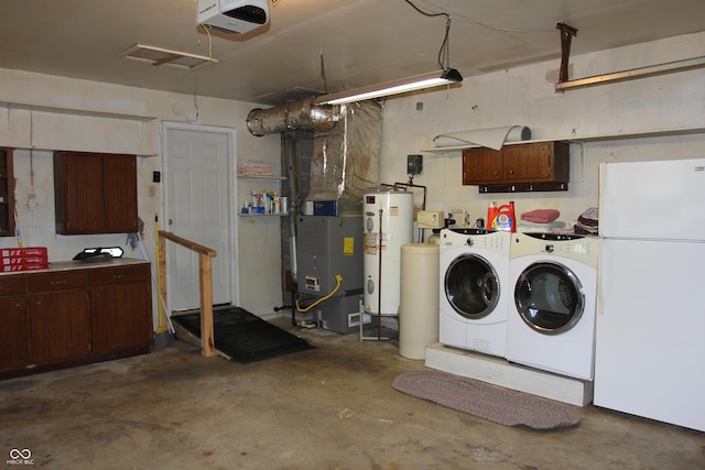 washroom featuring heating unit, cabinet space, water heater, a garage, and washing machine and dryer