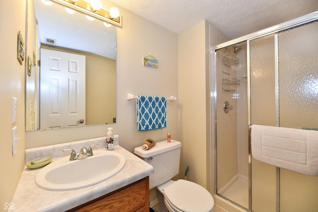 full bathroom with vanity, toilet, a shower stall, and a textured ceiling