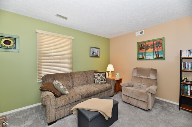 carpeted living area featuring baseboards, visible vents, and a textured ceiling