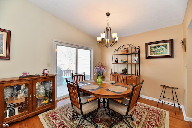 dining area featuring a notable chandelier, wood finished floors, baseboards, and vaulted ceiling