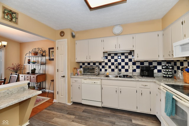 kitchen with dark wood finished floors, decorative backsplash, white cabinets, white appliances, and a sink