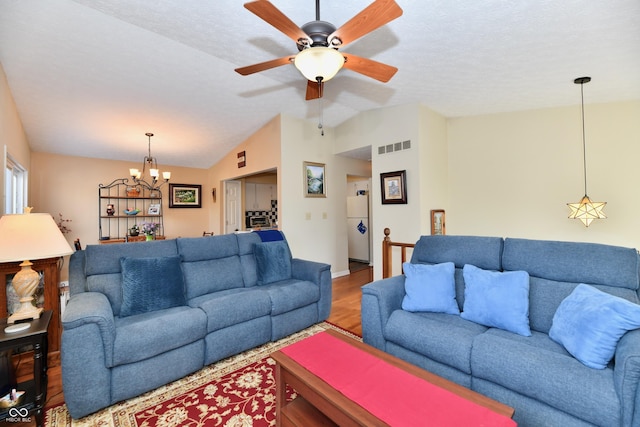 living area with visible vents, ceiling fan with notable chandelier, lofted ceiling, and wood finished floors