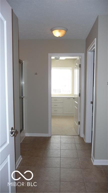 corridor with tile patterned flooring and baseboards