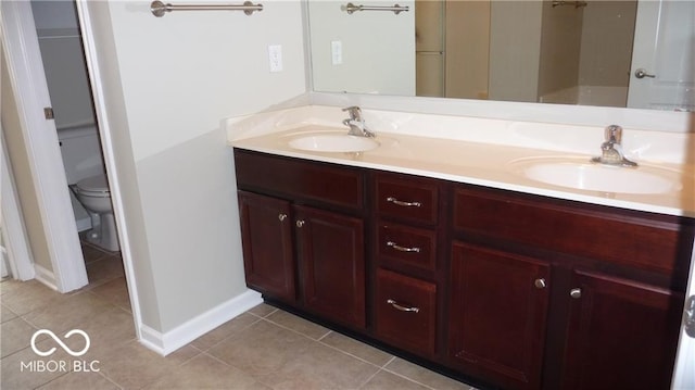 bathroom with tile patterned flooring, double vanity, toilet, and a sink