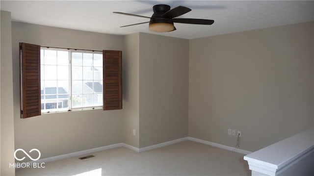 unfurnished room featuring light colored carpet, a ceiling fan, visible vents, and baseboards