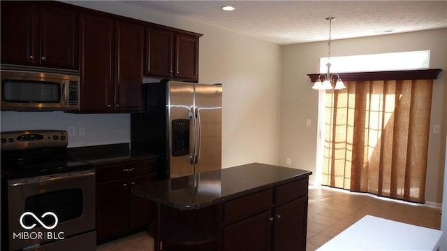 kitchen featuring decorative light fixtures, a center island, stainless steel appliances, an inviting chandelier, and dark brown cabinets