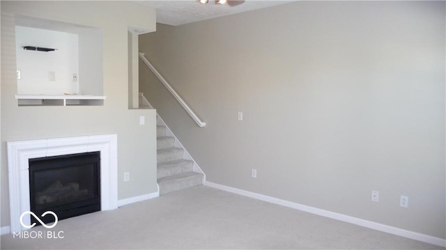 unfurnished living room featuring stairs, baseboards, carpet floors, and a fireplace