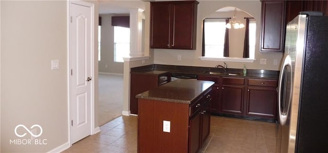 kitchen with a kitchen island, plenty of natural light, freestanding refrigerator, a sink, and dark countertops