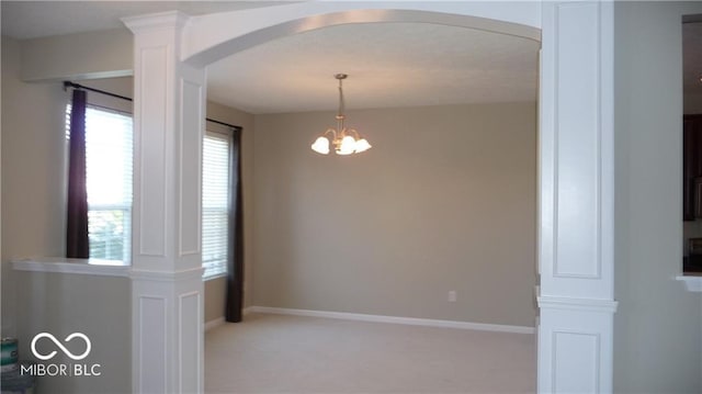 unfurnished room featuring arched walkways, a chandelier, light colored carpet, and baseboards