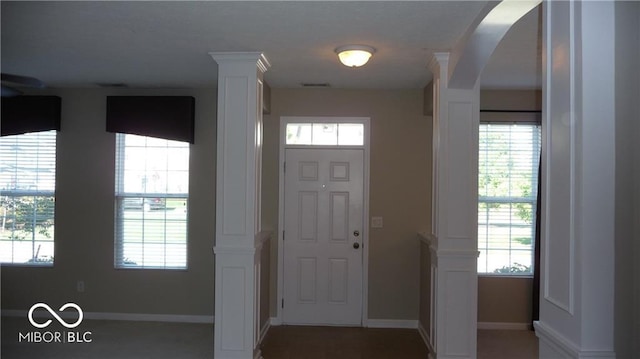 foyer featuring a wealth of natural light, baseboards, and arched walkways