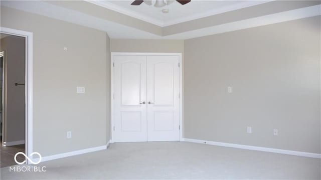 unfurnished bedroom featuring a closet, a raised ceiling, crown molding, and baseboards