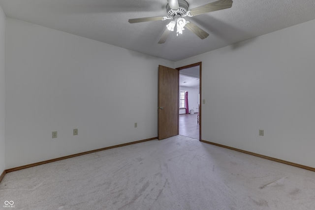 empty room featuring baseboards, light colored carpet, ceiling fan, and a textured ceiling