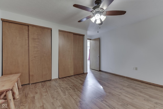 unfurnished bedroom with ceiling fan, two closets, and light wood-style flooring