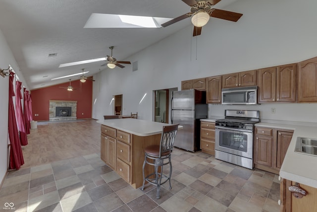 kitchen with stainless steel appliances, a kitchen island, a fireplace, and light countertops